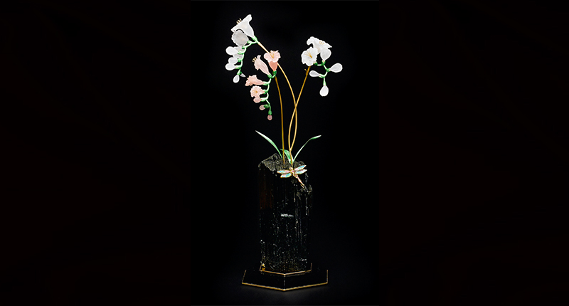 The base of the “Freesias with Dragonfly” piece by Manfred Wild is a large single crystal of green-black Brazilian tourmaline weighing nearly 800 carats, supporting three sprays of freesias crafted of frosted rock crystal or rose quartz on 18-karat gold stems. The removable dragonfly brooch features pink and Paraiba-type tourmalines and diamonds. The predicted sale price is $55,000 to $75,000. The base of the “Freesias with Dragonfly” piece by Manfred Wild is a large single crystal of green-black Brazilian tourmaline weighing nearly 800 carats, supporting three sprays of freesias crafted of frosted rock crystal or rose quartz on 18-karat gold stems. The removable dragonfly brooch features pink and Paraiba-type tourmalines and diamonds. The predicted sale price is $55,000 to $75,000.