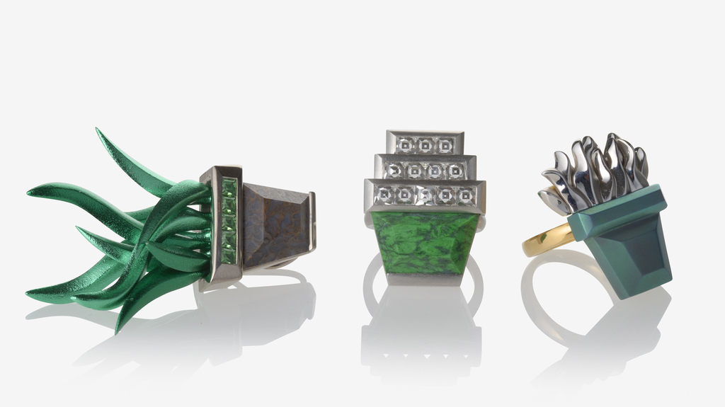 At left, an earring with fossilized dinosaur bone pot, green aluminum plant, and tsavorite accents set in white gold (sold as pair for $23,700); at center, the “Stacked Pots” ring with diamonds and Maw Sit Sit set in platinum ($42,300); and at right, titanium, gold, and platinum ring ($5,200) At left, an earring with fossilized dinosaur bone pot, green aluminum plant, and tsavorite accents set in white gold (sold as pair for $23,700); at center, the “Stacked Pots” ring with diamonds and Maw Sit Sit set in platinum ($42,300); and at right, titanium, gold, and platinum ring ($5,200)