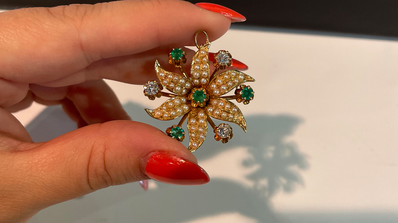 An antique starburst pendant, set with emeralds and seed pearls from the early 1900s