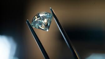 Stock image of a polished diamond in tweezers  